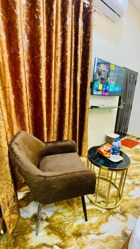 a chair and a table in front of a curtain at Holiday Guest House Lahore in Lahore
