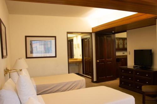 a hotel room with two beds and a television at J&A Classic Hotel in Lima