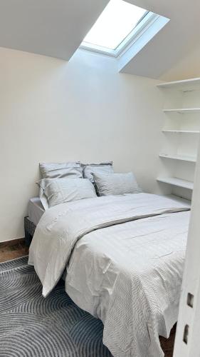 un lit dans une chambre blanche avec une fenêtre dans l'établissement Mezzanine 17 Rue de la Fraternité 2 chambres avec parking, à Drancy