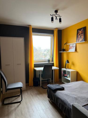a bedroom with a bed and a desk and a window at Cosy Rooms in Kraków