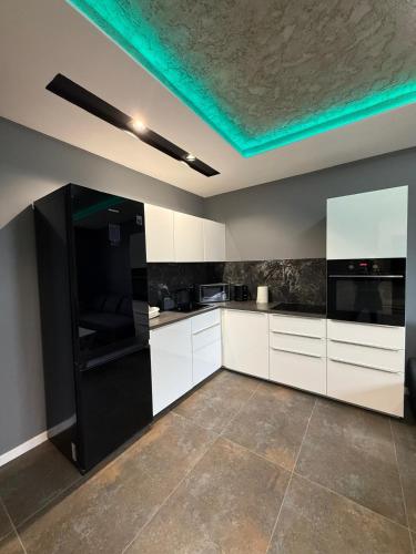 a kitchen with white cabinets and a black refrigerator at Apartament Centrum 3-pokojowy Klimatyzacja nr 4 in Radom