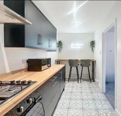 a kitchen with a stove and two stools at Zetland House Apartment - First floor with garden and parking in Southport