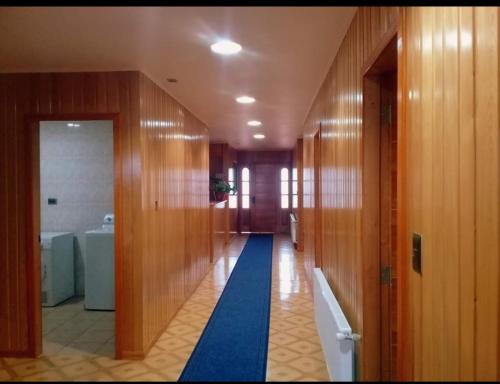 a hallway of a bathroom with wooden walls and a blue rug at 5mentarios Ltda in Dalcahue