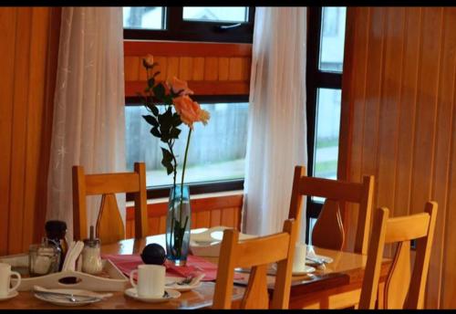 a dining room table with a vase with flowers in it at 5mentarios Ltda in Dalcahue