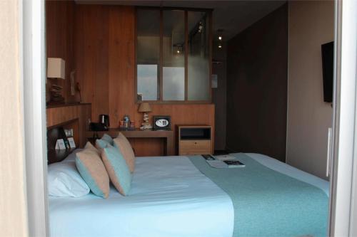 a bedroom with a large bed with pillows at Logis Hôtel Le Calluna Restaurant La Flottille in Préfailles