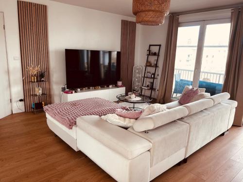 Cette chambre comprend un canapé blanc et une télévision. dans l'établissement Appartement T3 avec grand balcon, à Bordeaux