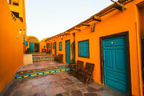 a row of orange buildings with blue doors and chairs at Fenti Nubian Resort in Aswan