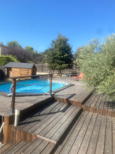 une terrasse en bois à côté d'une piscine dans l'établissement Maison au pied du Luberon, à La Motte-dʼAigues