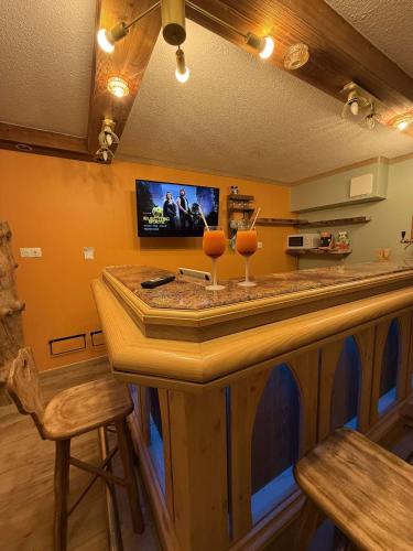 a kitchen with a bar with a tv on the wall at Le Savoyard - Bar & Jacuzzi in Bellevaux