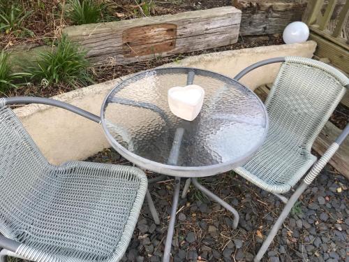 a table and two chairs with a cup on it at fAiRy DeLL Guesthouse, with cozy lockable rooms, tv, tea tray with choccies, free wifi and parking, 24hr check in, COA, all are welcome in Bradford