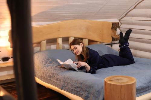 a woman laying on a bed reading a book at База відпочинку Forest Stream in Svalyava