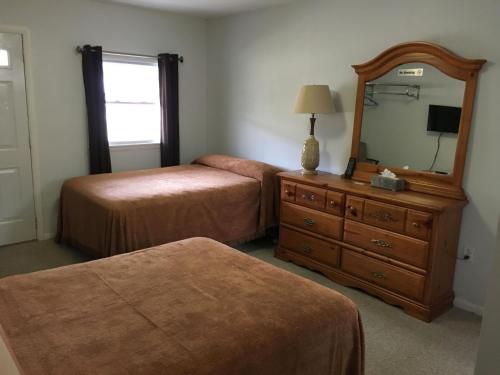 1 Schlafzimmer mit 2 Betten, einem Spiegel und einer Kommode in der Unterkunft McGregor Inn Motel in Saratoga Springs