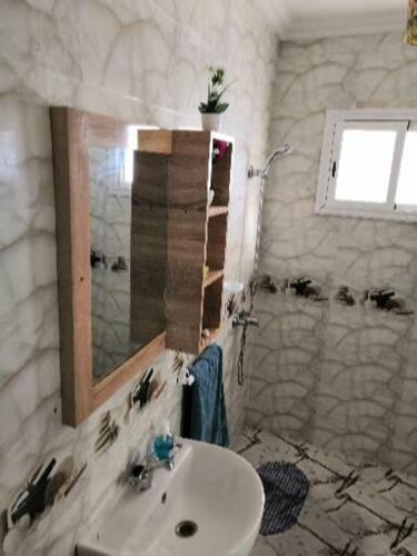 a white bathroom with a sink and a mirror at Yamna home in Agadir