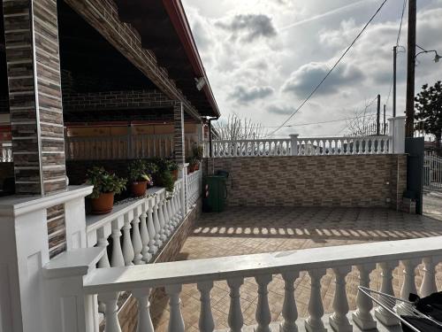 a white fence on a porch with potted plants at Gano Appartement in Katerini