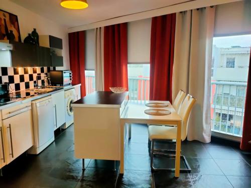 - une cuisine avec une table, des chaises et des rideaux rouges dans l'établissement Tu Casa parking fibre optique Netflix, à Saint-Raphaël