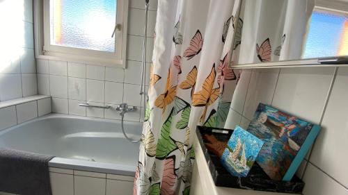 a bathroom with a tub and a shower curtain at Naturnahe Familienwohnung in Rüschegg-Graben