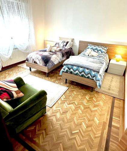 a bedroom with two beds and a green couch at Villa Serena B&B Seren del Grappa in Seren del Grappa