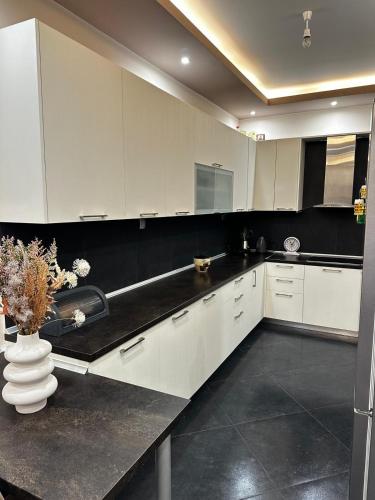 a kitchen with white cabinets and a vase of flowers at Gano Appartement in Katerini