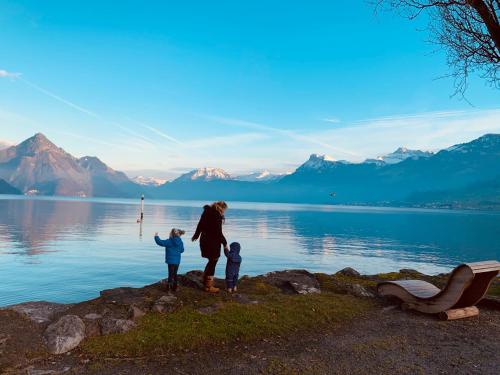 a woman and two children standing on the shore of a lake at Gartenoase by Greatlifestay in Ennetbürgen