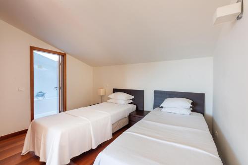 two beds in a room with white sheets at Baia da Luz Resort in Luz