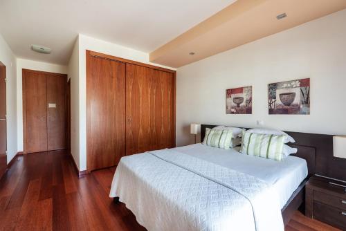 a bedroom with a white bed and a wooden cabinet at Baia da Luz Resort in Luz