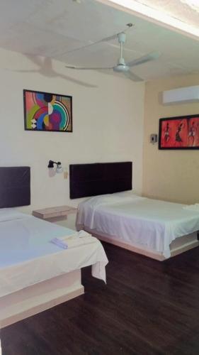 a room with two beds and paintings on the wall at Hotel Posada Quetzal in Arriaga