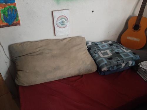 a bed in a room with a guitar next to a bed sidx sidx at Cytau mesa de trabalho e sofá-cama com ar condicionado, café, wi-fi e água liberados, acesso fácil in Porto Alegre