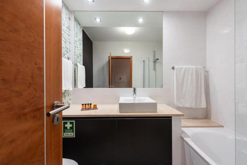 a bathroom with a sink and a large mirror at Baia da Luz Resort in Luz