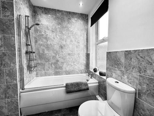 a bathroom with a toilet and a tub and a sink at Ocean Apartment, Spacious 5 bedroom holiday home in Whitley Bay