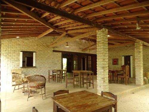 un patio con mesas y sillas y una pared de ladrillo en Jungle House, en São Miguel do Gostoso