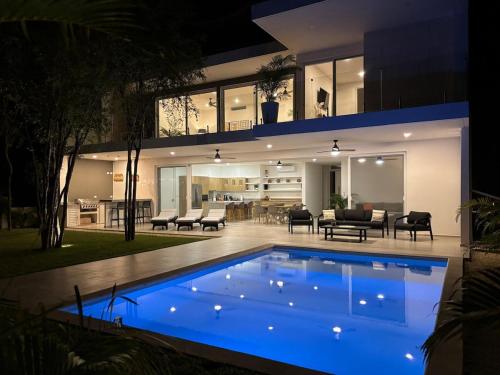 a house with a blue swimming pool at night at Villa Pasha , dream villa in Xpuha , Riviera Maya in Xpu Ha