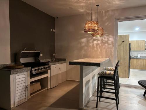 a kitchen with a stove and a bar with a stool at Villa Pasha , dream villa in Xpuha , Riviera Maya in Xpu Ha