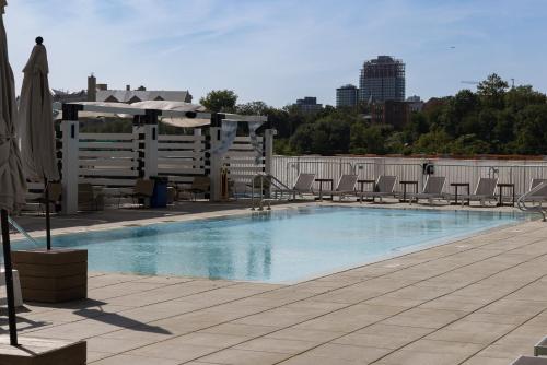 a swimming pool with chairs and umbrellas on a building at Chique Loft 15 Min from NYC with City View & Pool in Jersey City