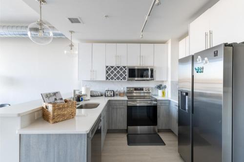 a kitchen with white cabinets and a stainless steel refrigerator at Chique Loft 15 Min from NYC with City View & Pool in Jersey City