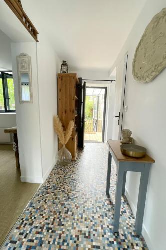 a hallway with a table and a tile floor at La maison du 1, Vexin in Gaillon-sur-Montcient