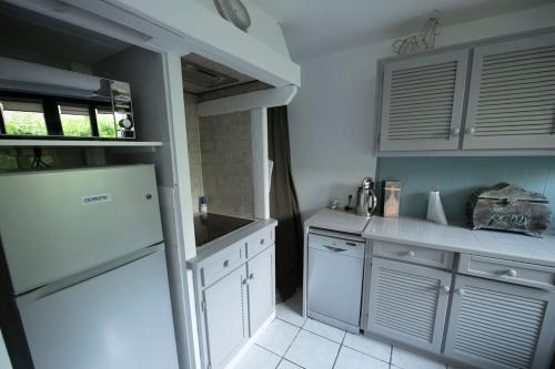 a kitchen with a white refrigerator and white cabinets at La maison du 1, Vexin in Gaillon-sur-Montcient