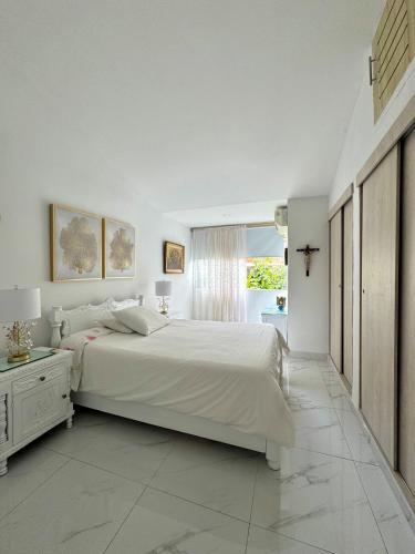 a white bedroom with a large bed and a window at House surrounded by nature in Cali