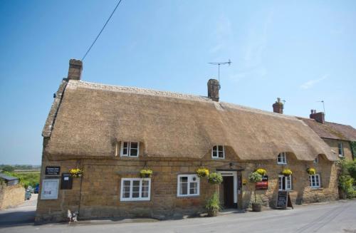an old stone building with a thatched roof at Masons Arms in Montacute