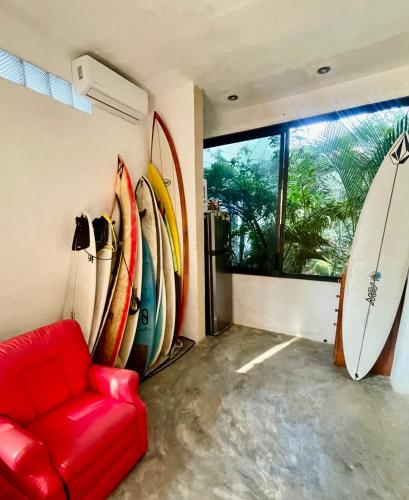 Brisas de ZicatelaにあるLa Punta SurfHouse AC Starlinkの赤いソファとサーフボードが壁に寄せられた部屋
