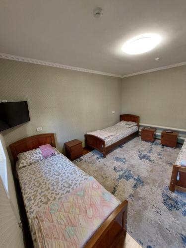 Una habitación con dos camas y un televisor de pantalla plana. en Hostel Room, en Tashkent