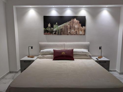 a bedroom with a large bed with a painting on the wall at Infinity House Catania in Catania