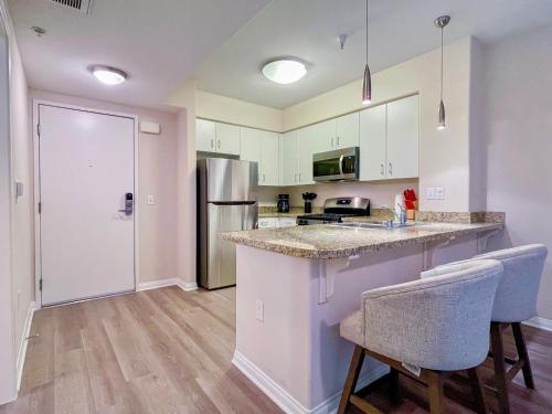 a kitchen with white cabinets and a counter with two chairs at Cozy Studio near Los Angeles Museum of Art in Los Angeles