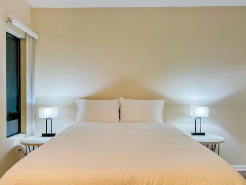 a bedroom with a large white bed with two lamps at Cozy Studio near Los Angeles Museum of Art in Los Angeles