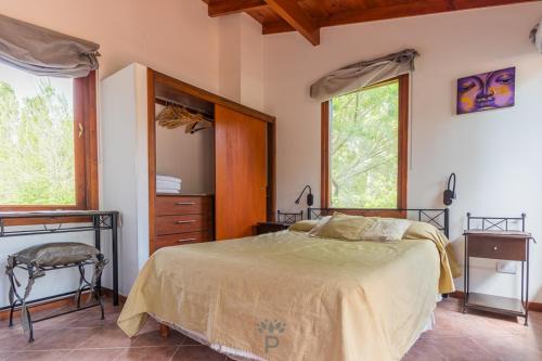 a bedroom with a bed and a dresser and two windows at PRANAMAR, apart del bosque in Santa Teresita