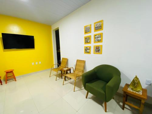 a living room with a green chair and yellow walls at Casa Miriti Hostel in Belém