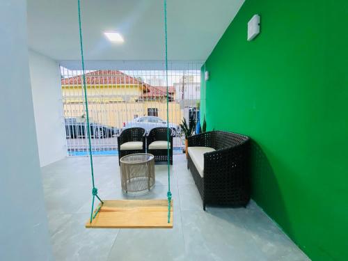 a swing in a room with a green wall at Casa Miriti Hostel in Belém