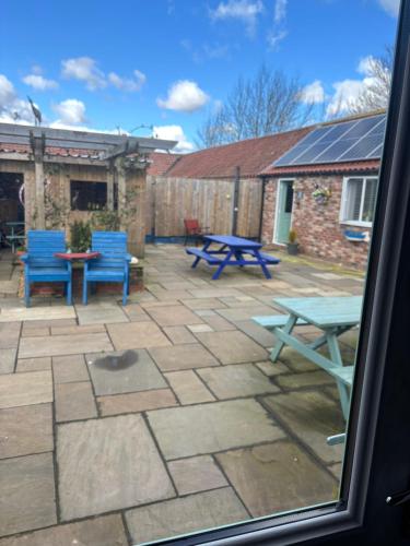 a patio with blue picnic tables and blue chairs at The Feed Room At Eastmoor Farm Fully Renovated Fully Equipped 2 Bed Luxury Mews Cottage 1 Mile from the Beach in Bridlington