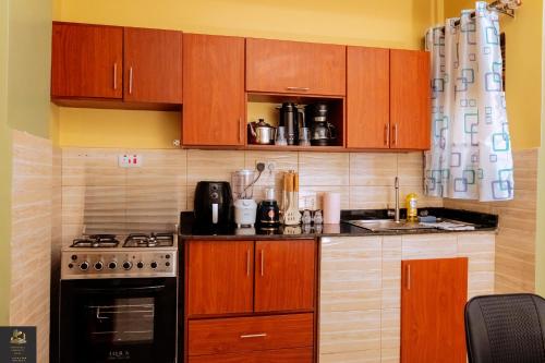 a small kitchen with wooden cabinets and a stove at Safa Homes and Residences in Kampala