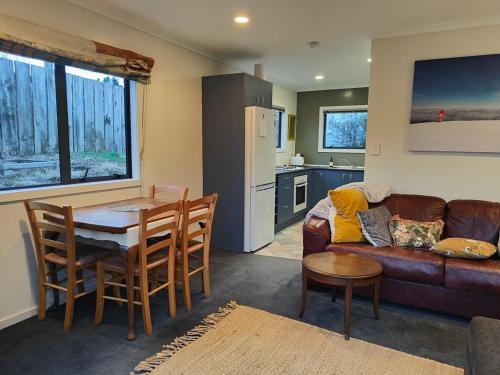 Una sala de estar con un sofá y una mesa y una cocina. en Ohakune Peak Retreat Unit 2, en Ohakune