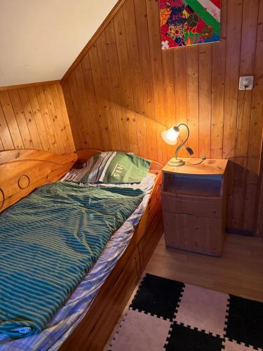 a bed in a wooden room with a lamp on a table at International Family Guesthouse in Schüpfheim